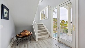 A staircase with a view of a pool and palm trees, a wooden bench, and a framed picture on the wall.