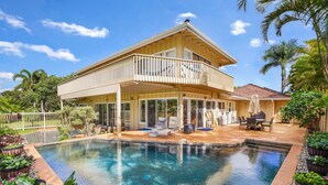 Una casa de dos pisos con un balcón grande y una piscina.