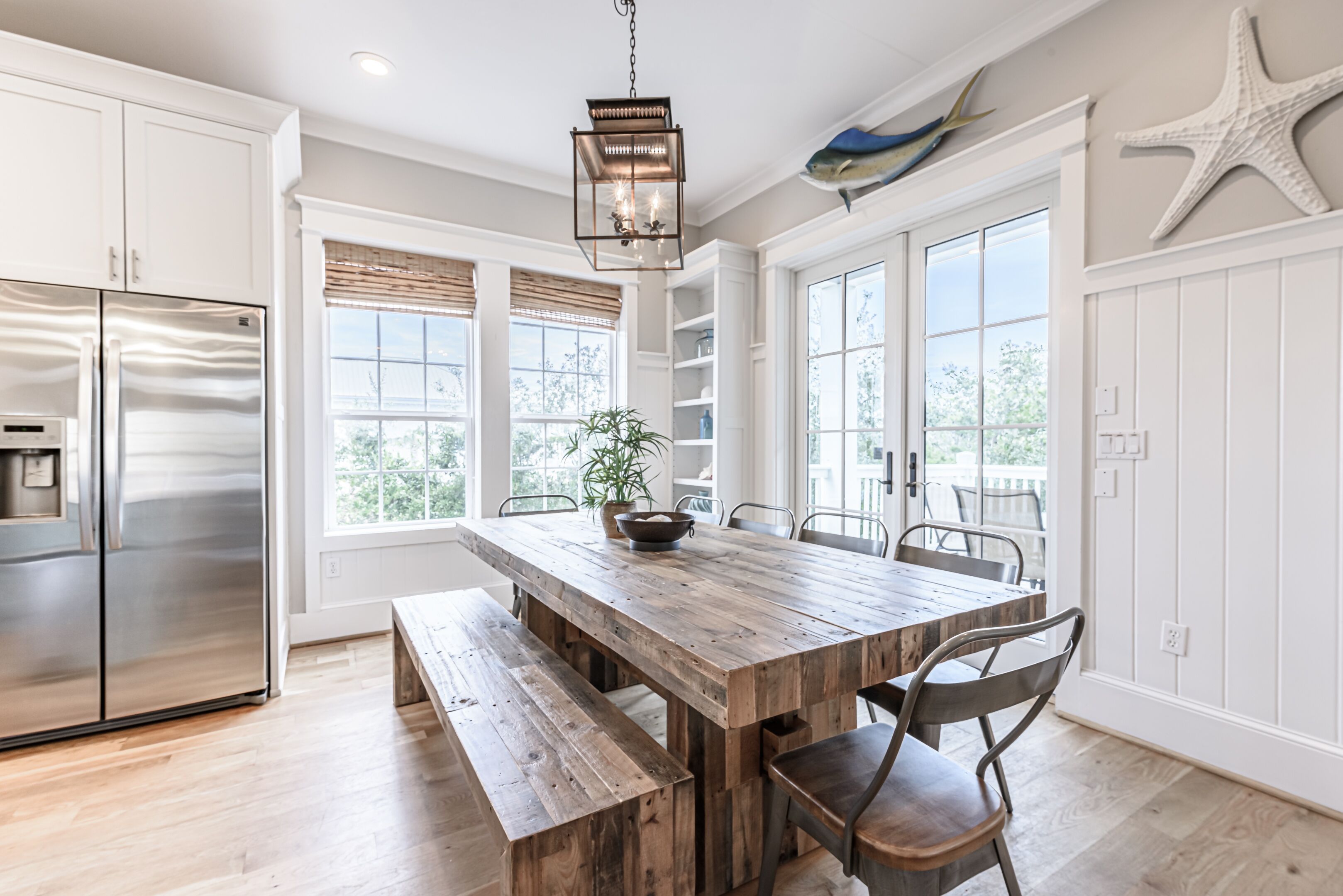 A kitchen with a wooden table, built-in cabinets, a stainless steel refrigerator, and a hanging light fixture.