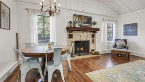 A dining area with a round table and chairs, a fireplace, and a chandelier.