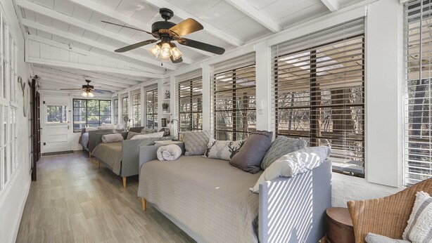 A spacious room with a large bed, two sofas, and a ceiling fan.