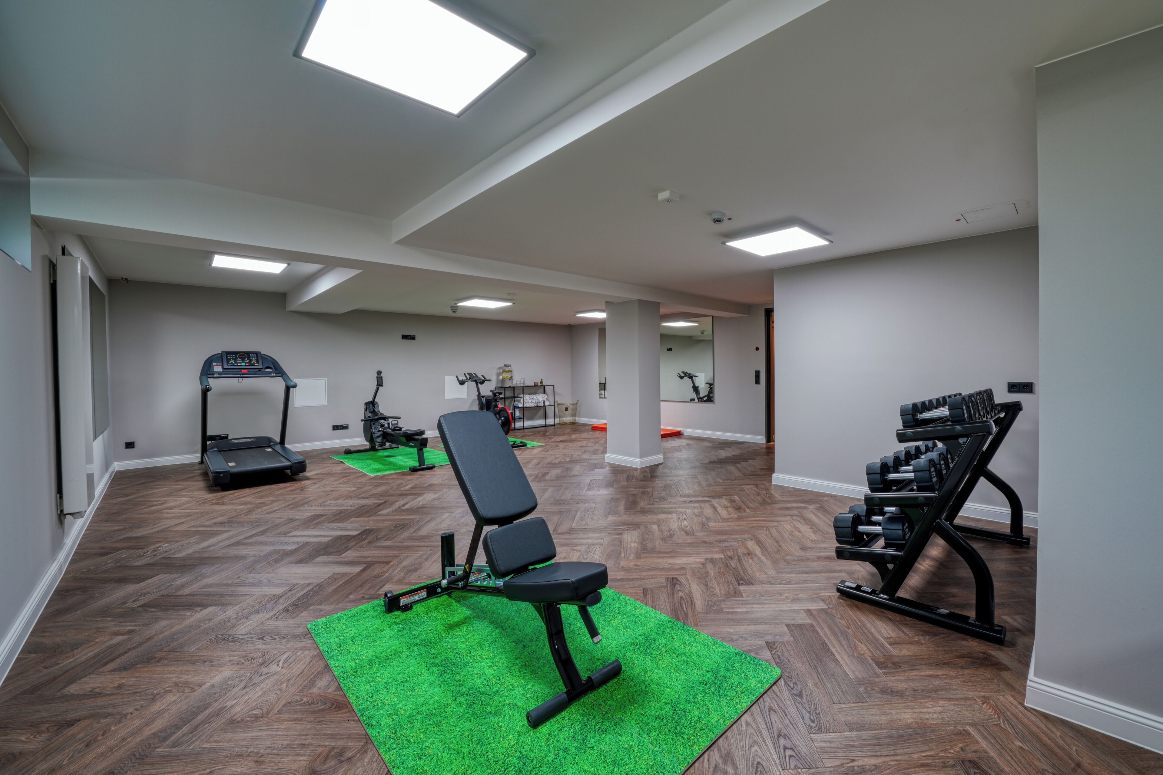 Ein Fitnessraum mit Trainingsgeräten, Laufband und Gewichtheck.