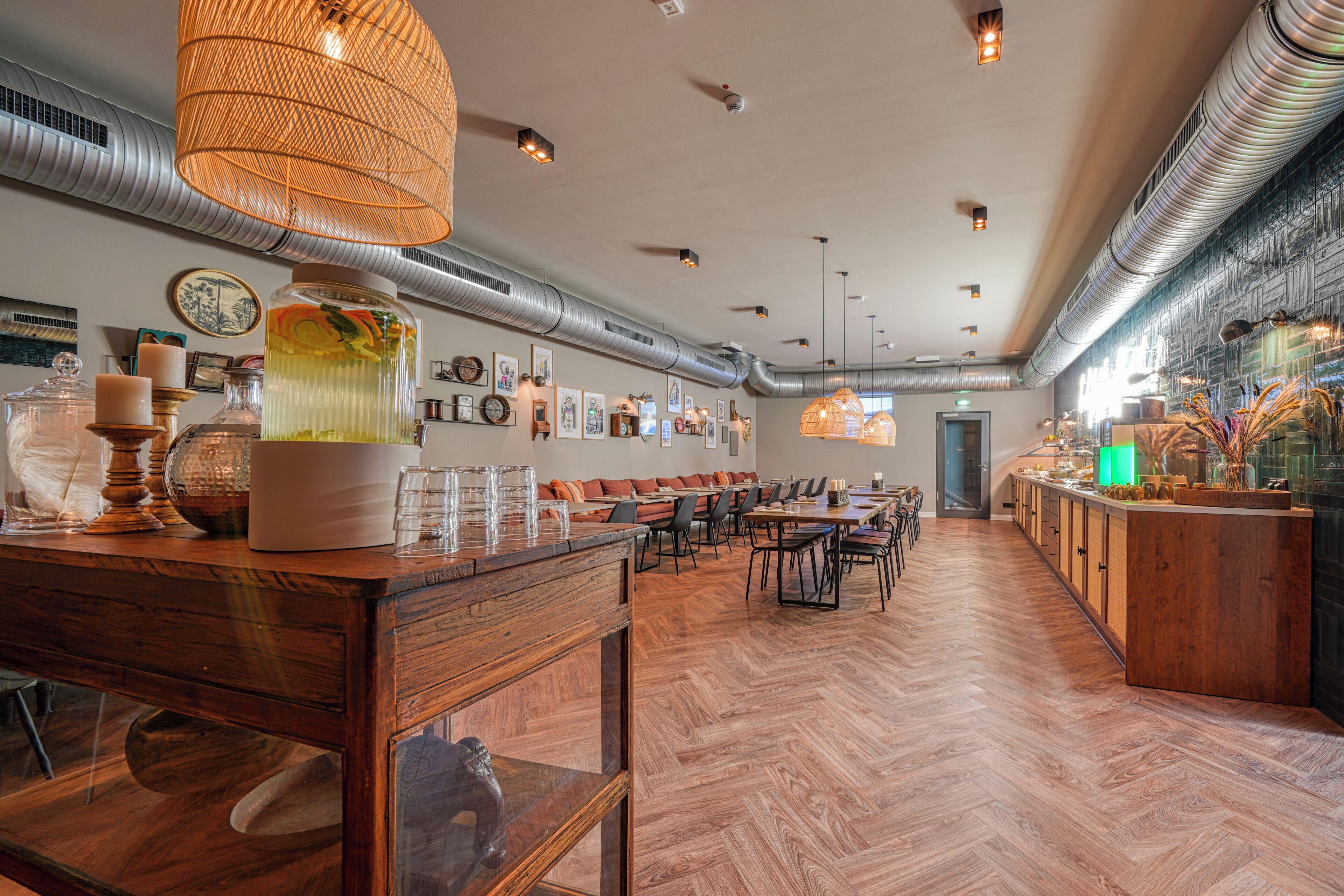 A spacious restaurant with wooden flooring, a long counter, and a variety of seating options.
