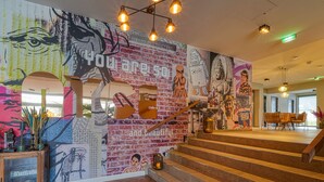 Una escalera con un mural colorido, escalones de madera y una zona de estar con una mesa y sillas.