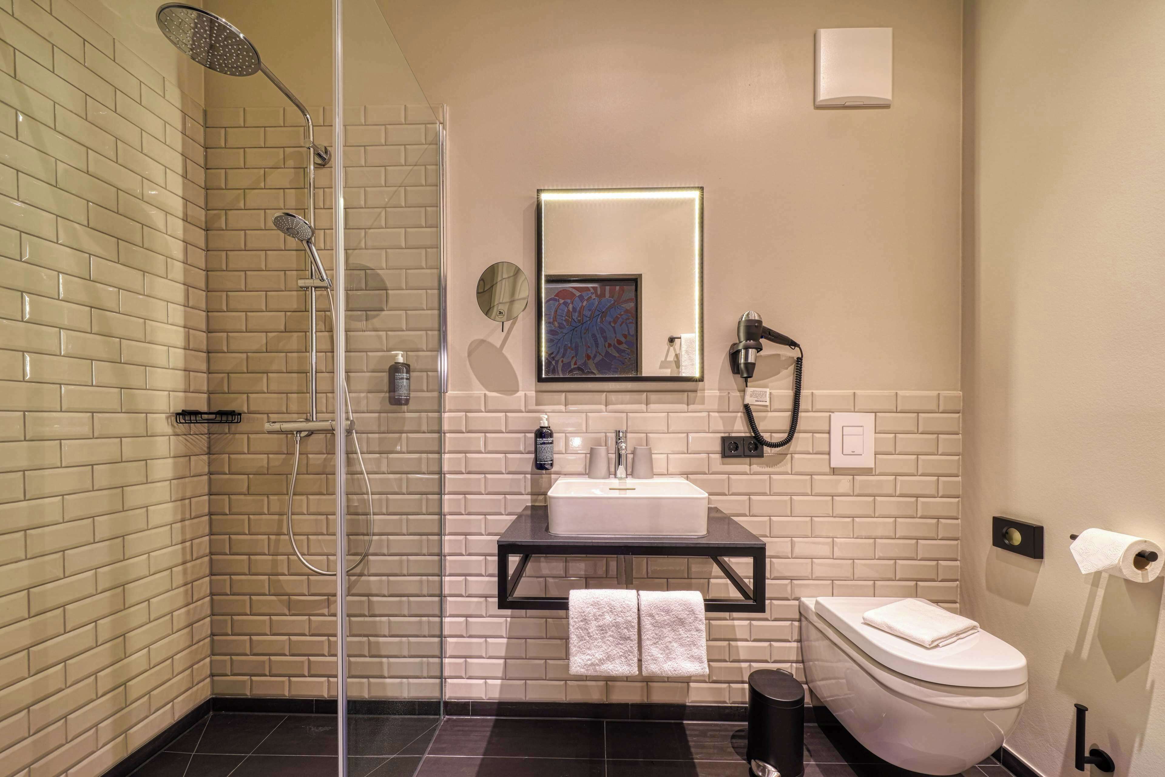 Een moderne badkamer met douche, toilet en wastafel.