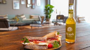 A sandwich on a plate with a bottle of Fritz-Spritz beer on a wooden table.