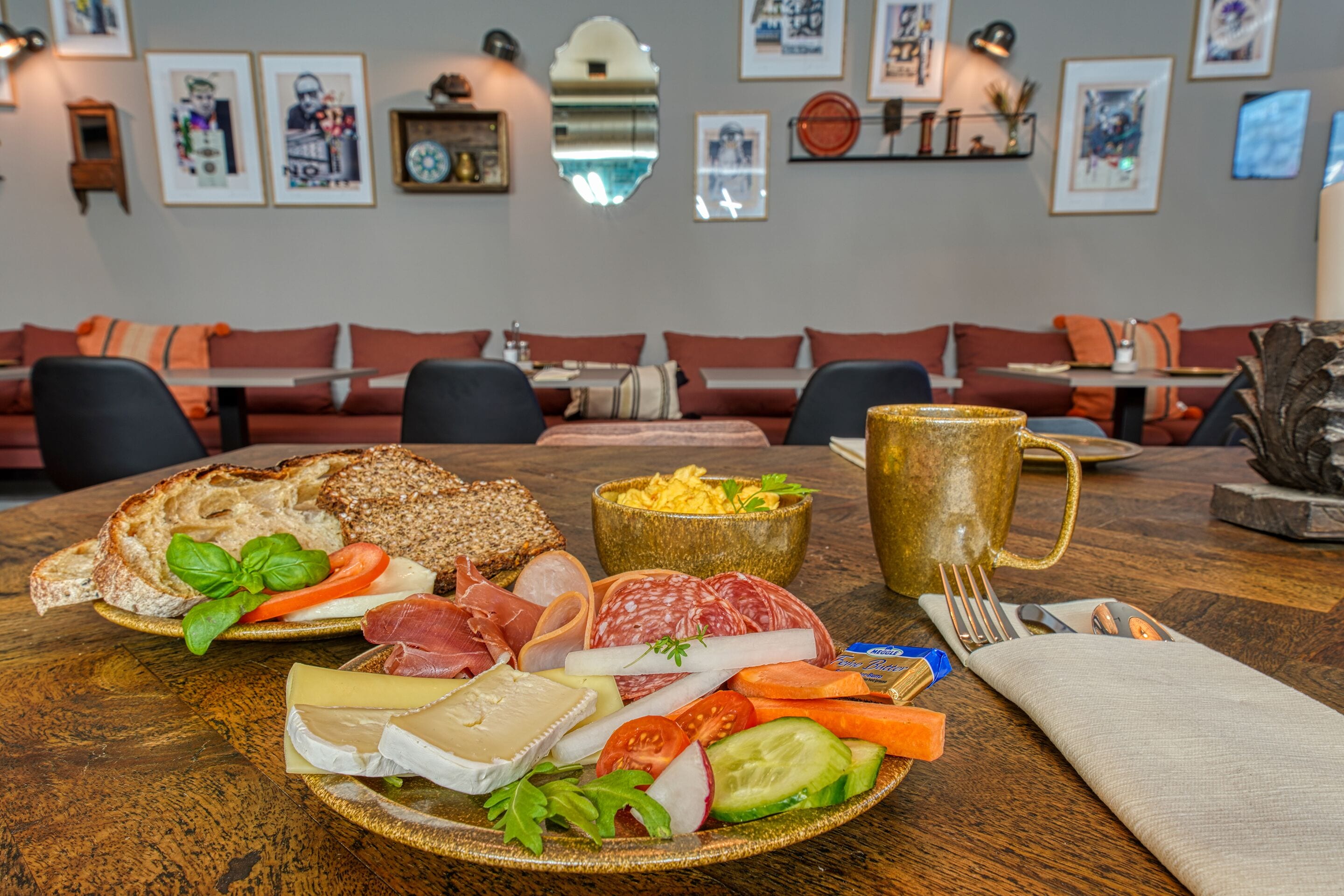Una mesa de comedor con diversos alimentos, como pan, queso, carnes y verduras.