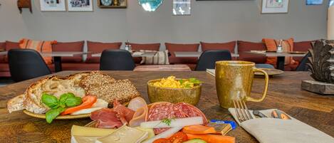 Una mesa de comedor con diversos alimentos, como pan, queso, carnes y verduras.