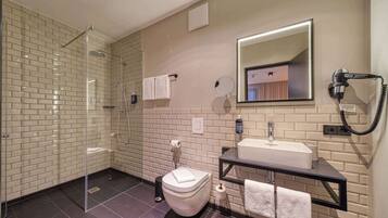 A modern bathroom with a glass-enclosed shower, a toilet, a sink with a mirror, and a hairdryer on the wall.