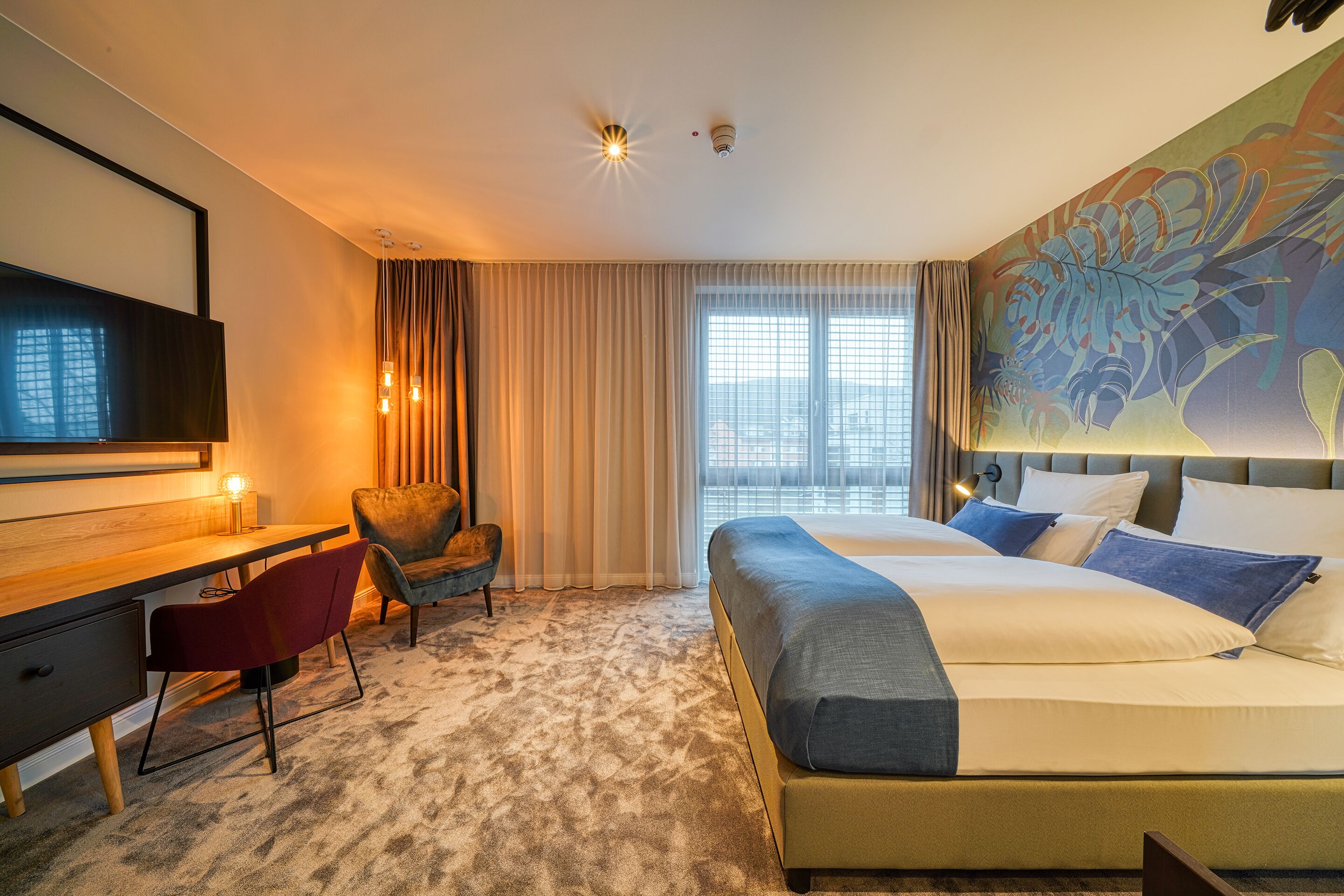 Een hotelkamer met een groot bed, een bureau, een stoel en een televisie.