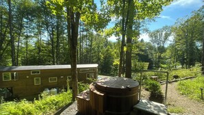 A rustic cabin with a wooden exterior, surrounded by dense forest. - Custom-built Tiny House on forested lot near Quechee (Hartland)