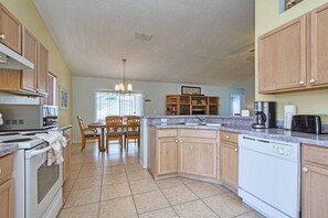 A kitchen with wooden cabinets, a dining area with chairs, a chandelier, and a built-in oven.