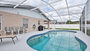 Une piscine extérieure couverte, dotée de chaises longues et d’un espace barbecue.