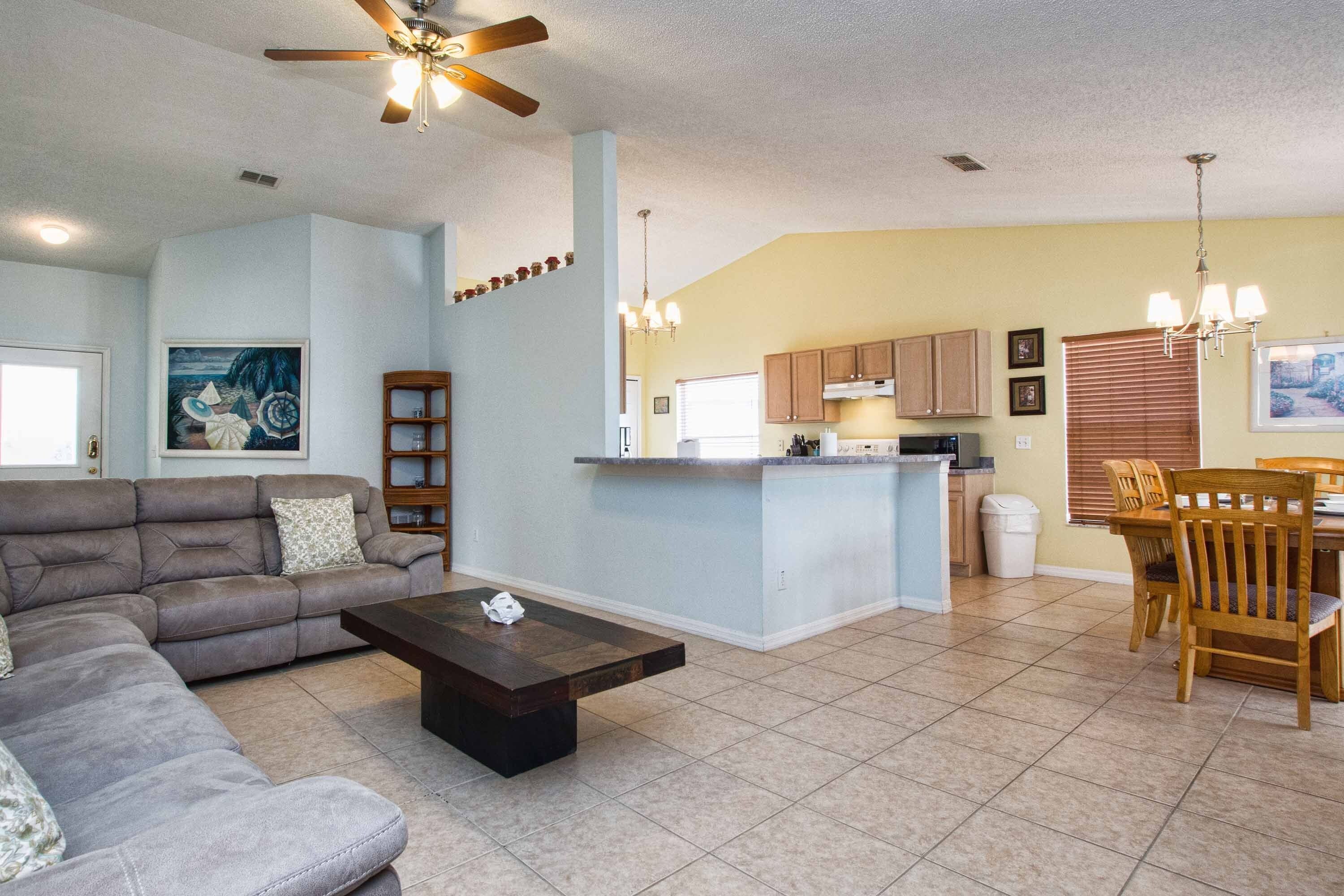 A living room with a sofa, coffee table, and a ceiling fan.