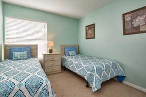 A bedroom with two beds, a nightstand, a dresser, and a window with blinds. - Indian Ridge- 4 Bedroom Pool Home- 2405IR 4 Home by RedAwning (Kissimmee)