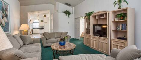 A living room with a sofa set, a coffee table, a TV, and a bookshelf.