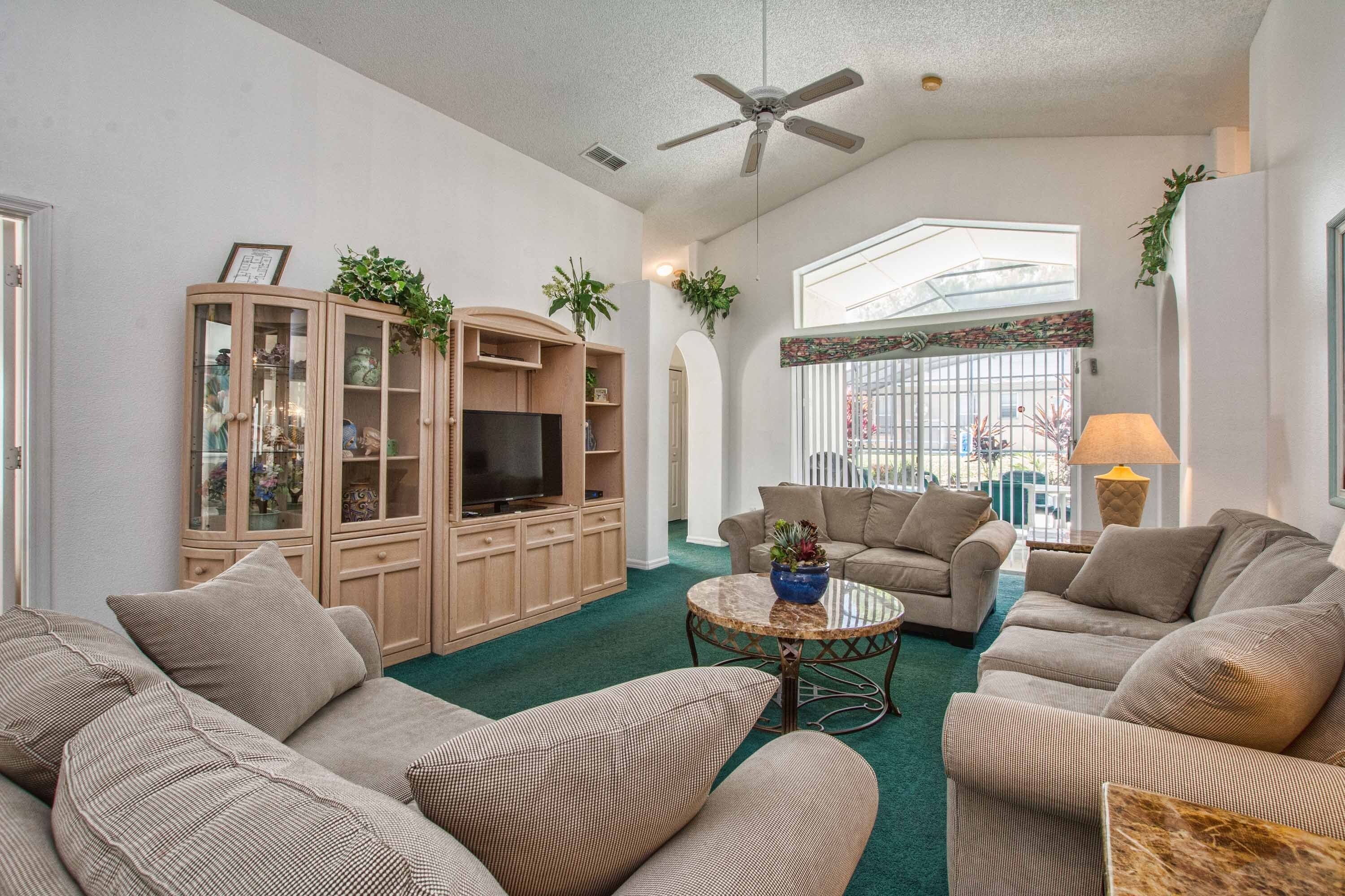 A living room with a large cabinet, two sofas, a coffee table, and a ceiling fan.