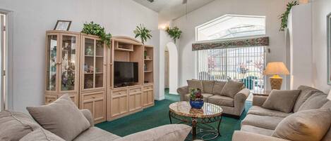 A living room with a large cabinet, two sofas, a coffee table, and a ceiling fan.