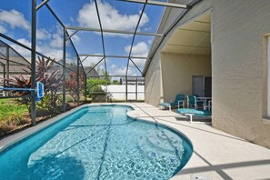 Ein Schwimmbecken mit Glasveranda, umgeben von Liegestühlen und einem weißen Zaun.