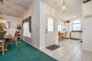 A spacious kitchen with white cabinets, a refrigerator, and a dining area with a table and chairs.