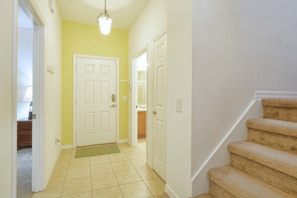 A hallway with a carpeted floor, a door, and a staircase.