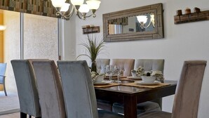 Uma sala de jantar com uma mesa de madeira, cadeiras acolchoadas e um candelabro.