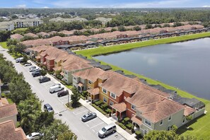 A residential area with row houses, a parking lot, and a body of water. - Paradise Palms- 4 Bed Townhome W-splashpool-3091pp 4 Bedroom Townhouse by RedAwning (Kissimmee)