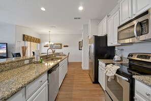 A modern kitchen with granite countertops, stainless steel appliances, and a central island. - Paradise Palms- 4 Bed Townhome W-splashpool-3091pp 4 Bedroom Townhouse by RedAwning (Kissimmee)