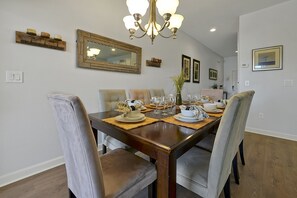 A dining room with a wooden table, four chairs, a chandelier, and wall-mounted decor. - Paradise Palms- 4 Bed Townhome W-splashpool-3091pp 4 Bedroom Townhouse by RedAwning (Kissimmee)