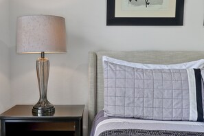 A neatly made bed with a quilted pillow and a lamp on a bedside table.