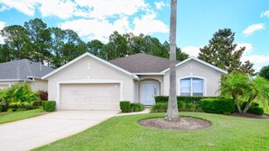 A single-story house with a garage, a well-maintained lawn, and a palm tree.