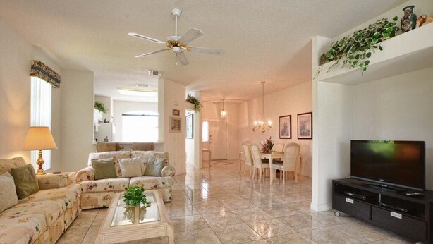A spacious living room with a sofa set, a coffee table, a TV stand, and a dining area with a chandelier.
