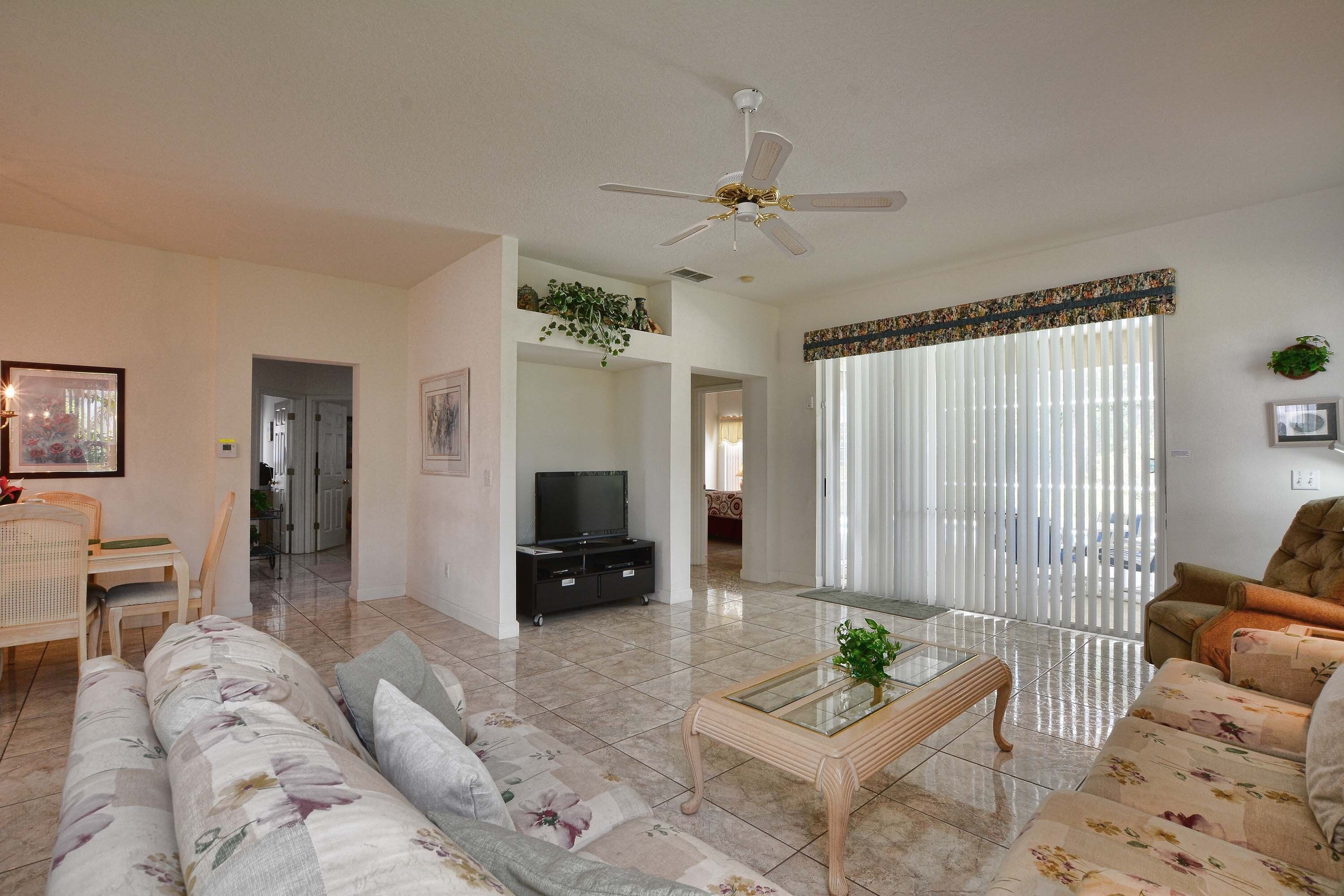 A living room with a sofa, coffee table, TV, and a ceiling fan.