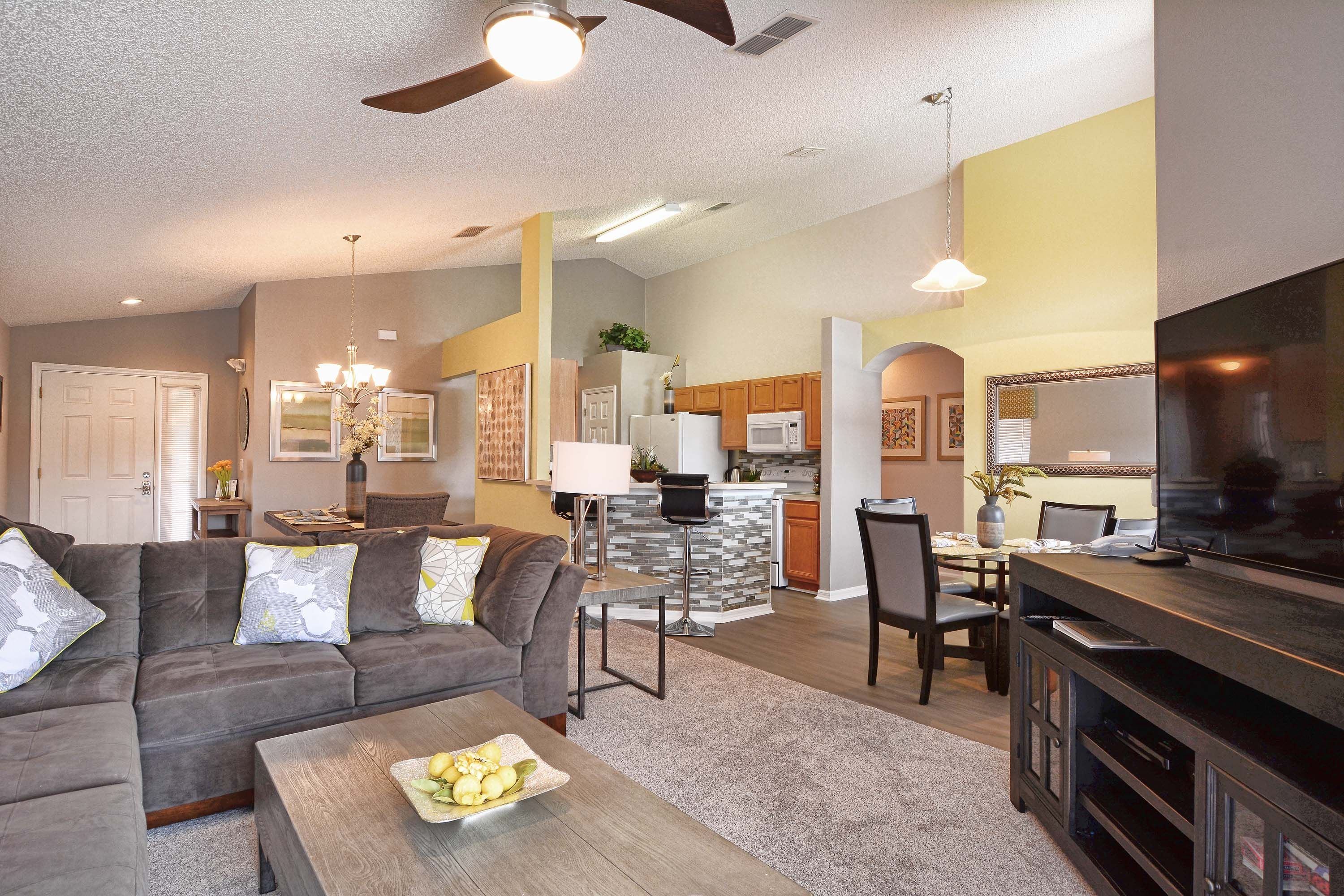 A modern living room with a sofa, coffee table, and a dining area with chairs and a table.