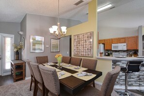 A dining area with a table set for four, surrounded by upholstered chairs.