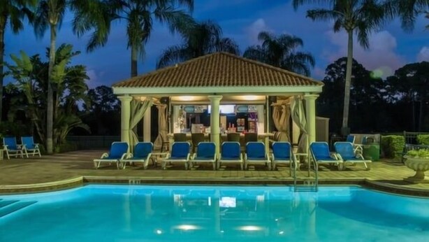 A poolside area with a covered seating area and lounge chairs. - Emerald 4 bedrooms with Pool - 2201Em 4 Home by RedAwning (Kissimmee)