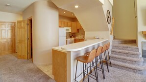 A modern kitchen with a central island, wooden cabinets, and a staircase leading to an upper level. - Pet Friendly, Slope-side, Spacious Town Home - ER21 by Redawning (Copper Mountain)