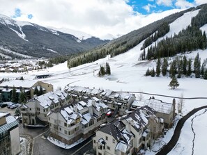 Un pueblo cubierto de nieve con edificios de varios pisos, una pista de esquí y un río.