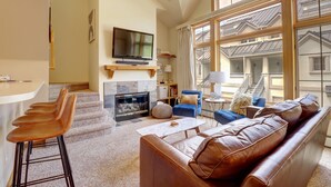 A modern living room with a fireplace, leather sofa, and a television. - Pet Friendly, Slope-side, Spacious Town Home - ER21 by Redawning (Copper Mountain)