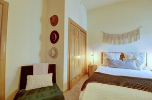Un dormitorio con cama, mesitas de noche, un armario y un colgante de macramé.