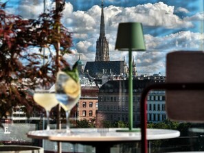 Ein Tisch mit einer grünen Lampe und zwei Weingläsern, mit Blick auf ein historisches Gebäude und eine Kirche im Hintergrund.