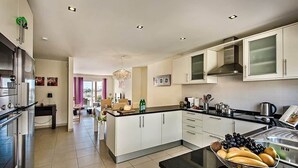 A modern kitchen with a central island, stainless steel appliances, and a dining area with a view.