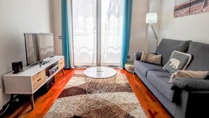 Un salon moderne avec un canapé, une table basse et un téléviseur posé sur un meuble blanc.