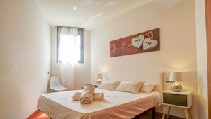 Une chambre à coucher comprenant un lit, des lampes de chevet, une chaise, une fenêtre avec des rideaux et un élément de décoration murale.