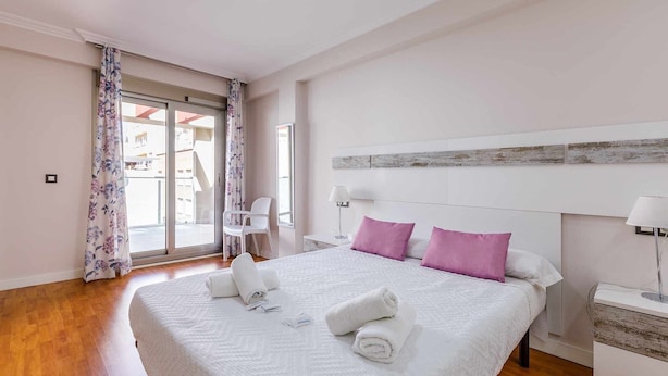 A hotel room with a large bed, a nightstand, a chair, and a view through a glass door. - A&n La Cueva 1 . (Torre del Mar)