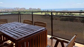 A balcony with a wooden table and chairs, a metal fence, and a view of a cityscape and coastline. - A&N La Vega 6, (Torre del Mar)