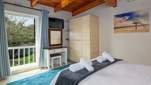A bedroom with a bed, a desk, a wardrobe, and a balcony with curtains. - San Lameer Villa Rentals 3104 (Southbroom)