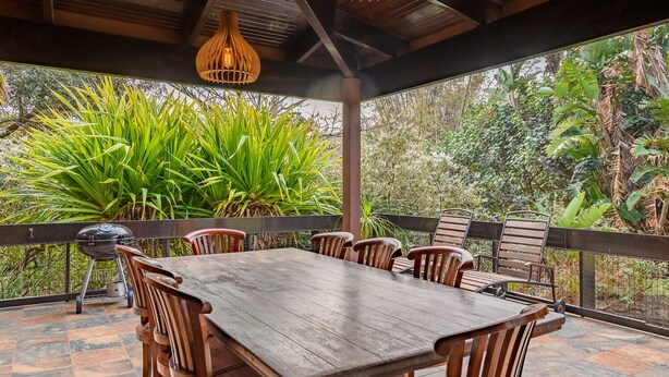A covered outdoor dining area with a wooden table and chairs, surrounded by lush greenery. - San Lameer Villa Rentals 3104 (Southbroom)