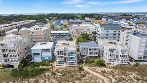 A coastal residential area with modern multi-story buildings, a sandy beach, and a clear view of the ocean. - Silver Sands 102S Direct Ocean Front, Just steps to the Beach! (Ocean City)