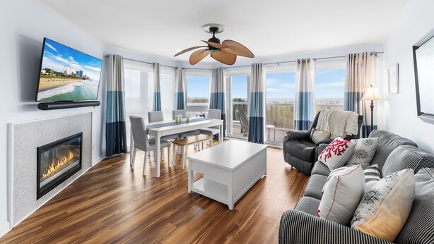 A modern living room with a fireplace, a dining area, and a sofa. - Silver Sands 102S Direct Ocean Front, Just steps to the Beach! (Ocean City)